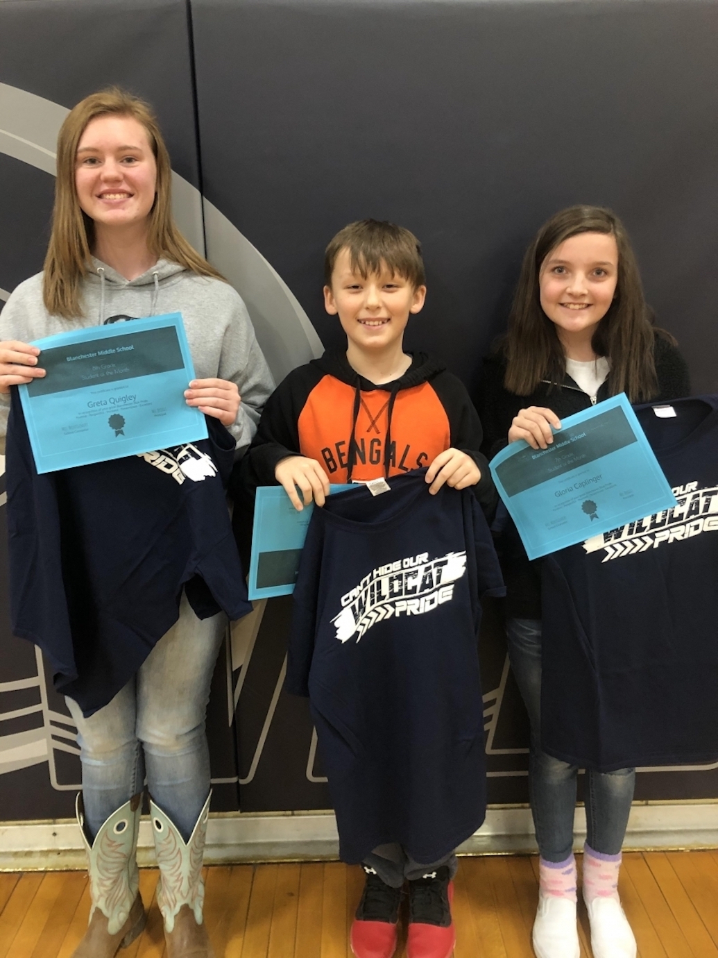 Greta, Aiden, and Gloria holding shirts and certificates